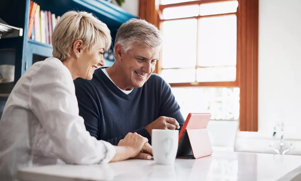 Two people looking at their tablet smiling 