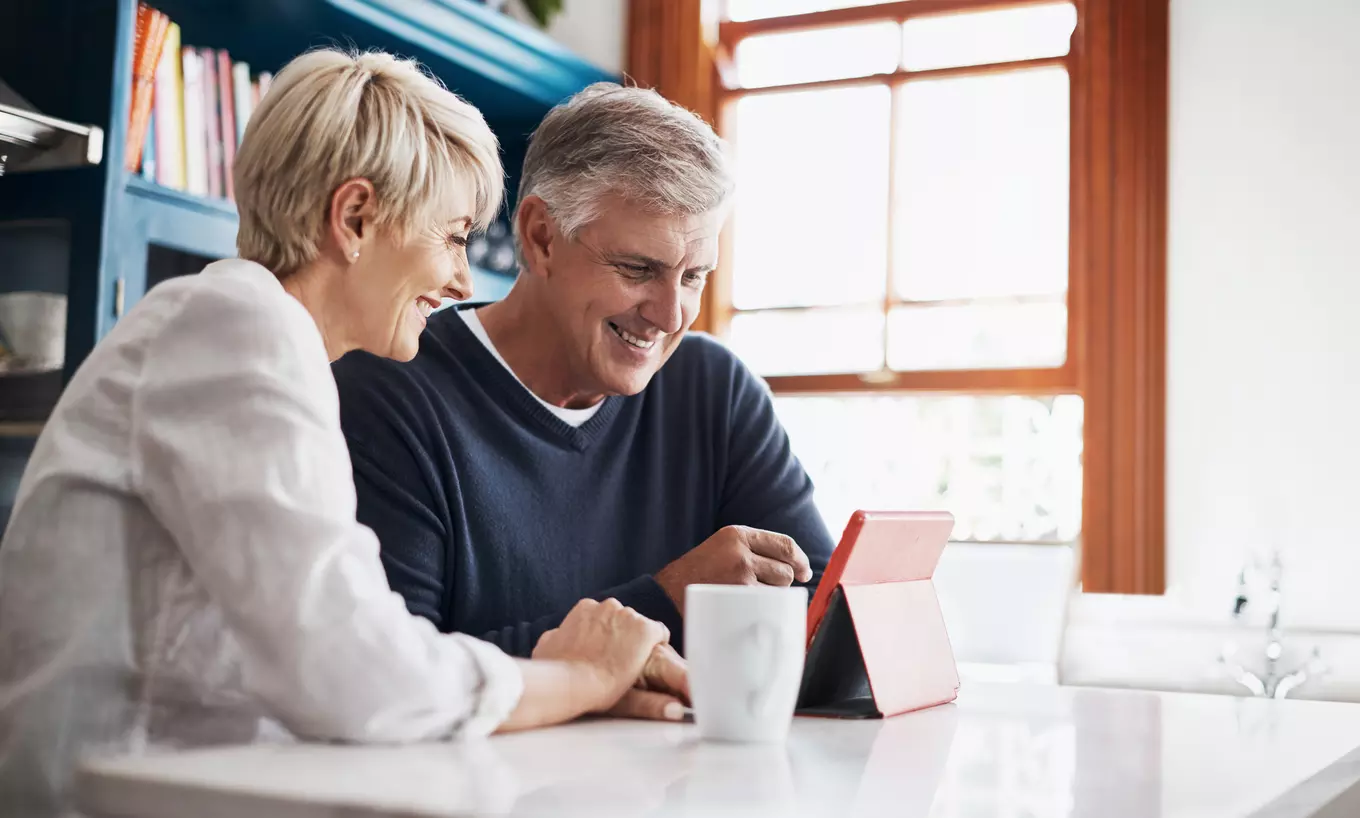 Two people looking at their tablet smiling 